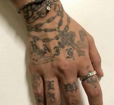 a man with tattoos on his hand and wrist is wearing a chain ring around his finger