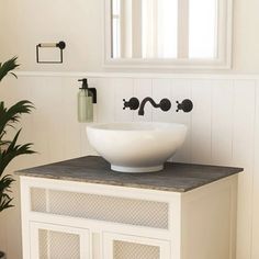 a white sink sitting on top of a counter next to a potted green plant