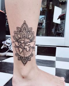 a woman's foot with a tattoo design on the side of her leg,