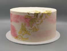 a white and pink cake with gold leaf decorations