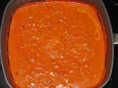 a casserole dish filled with red sauce on top of a black stovetop