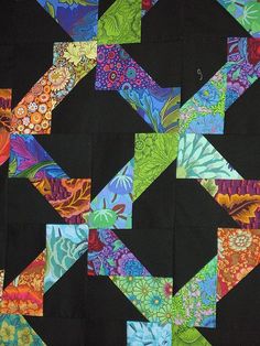 an image of a quilt made with different colors and patterns on black fabric, which has been cut into squares