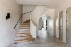 a long hallway with stairs leading up to the second floor and another room on the other side