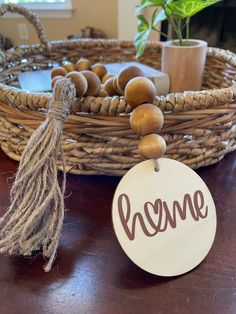 a wooden sign that says home next to a wicker basket with beads and a tassel