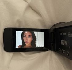 a woman's face is shown on the screen of a cell phone, which appears to be being used as a video camera