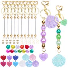 several different colored beads and charms hanging from hooks on a white background with hearts, seashells, starfish