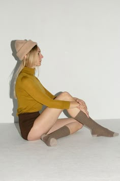 a woman is sitting on the floor with her legs crossed wearing socks and a hat