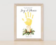 a christmas card with a yellow hand and holly wreath on it, in front of a white wall