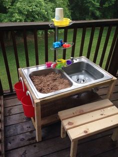 a sink and bench on a deck with trees in the background