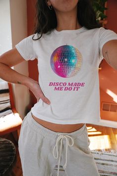 Looking for the perfect, most iconic disco ball baby tee to steal the show? We've got you covered with this fun "Disco made me do it" Disco Ball Baby Tee - bringing your Y2K outfit dreams to life! Our adorable Y2K baby tees will become your new favorite disco ball shirt from the first wear! The cutest gift for yourself or your fellow disco ball lovers! ABOUT THE TEE: - 100% USA cotton (Please note: The Ash Gray variation includes 90% Cotton & 10% Polyester for that authentic touch) - Ribbed knit crew neckline and a convenient tear-away label - Embrace that 90s style with a fit reminiscent of the iconic baby tees of the era--check out our size chart for specifics - Collection: Gildan 5000B* *PLEASE NOTE: The Gildan 5000B is a "youth" t-shirt. Just like the authentic baby tees of the 90s, ex Disco Style Cotton Short Sleeve Tops, White Rave Crew Neck Top, Disco Style Cotton Top With Short Sleeves, Retro Party Tops With Graphic Print, Retro Graphic Print Party Tops, Retro Graphic Print Tops For Party, Retro Cotton Party Tops, White Graphic Print Top For Rave, Fitted Disco T-shirt For Summer