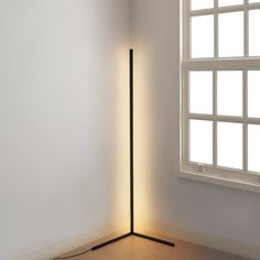 a floor lamp sitting next to a window in a room with white walls and wooden floors