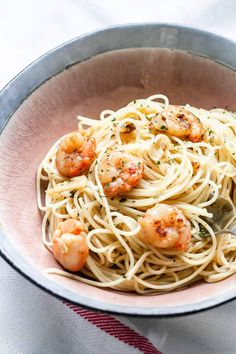 a bowl filled with pasta and shrimp on top of a table