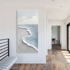 a painting on the wall in a room with wood flooring and white walls, along with a bench