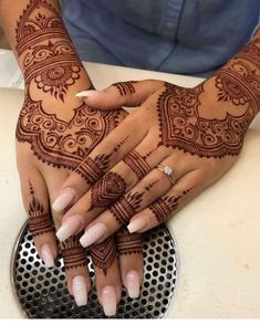 two hands with henna tattoos on them and one holding the other's hand