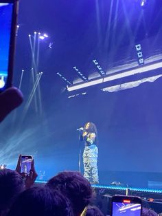 a man standing on top of a stage holding a cell phone in front of him