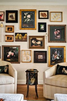 a living room filled with lots of framed pictures on the wall next to two couches