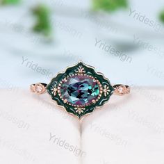 a ring with a blue and green stone in the center on top of a white surface