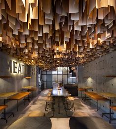 the interior of a restaurant with wooden tables and benches, suspended lights and lighting fixtures