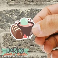 a hand holding up a sticker with a chocolate dessert in the middle on it