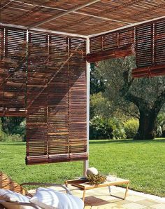 an outdoor area with chairs, tables and wooden shades on the roof over looking grass