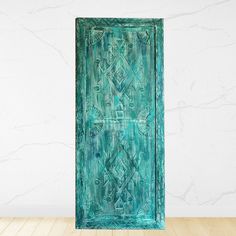 an old green door is sitting on a wooden floor in front of a white wall