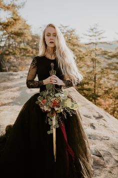 Woman with long blond hair wearing black lace wedding dress holding sword bouquet at Red River Gorge Lotr Bouquet, Elven Wedding Bouquet, Viking Wedding Bouquet, Wedding With Swords, Ren Fair Wedding, Alt Wedding Hair, Alternative Wedding Hair, Warhammer Wedding, Nature Wedding Ideas