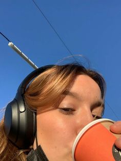 a woman wearing headphones drinking from a cup