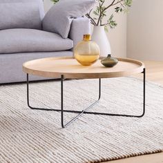 a living room with a couch, coffee table and vase on the rug in front of it