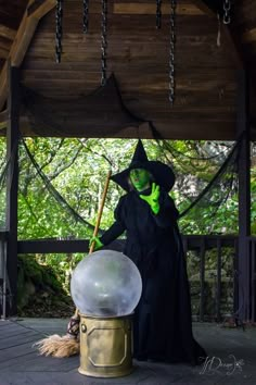 a man dressed as a witch holding a broom and standing next to a large crystal ball