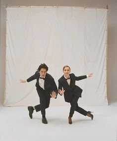 two young men in tuxedos are posing for a photo with their arms outstretched