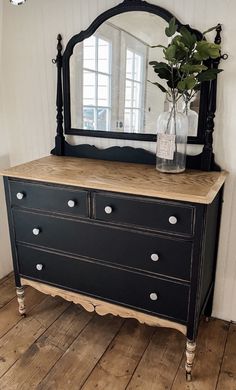 a black dresser with a mirror and vase on top