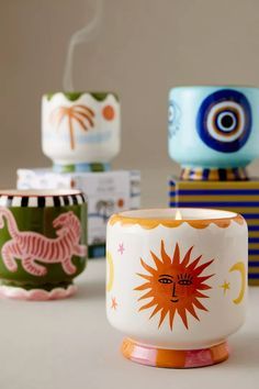 four different colored cups sitting next to each other on top of a white countertop