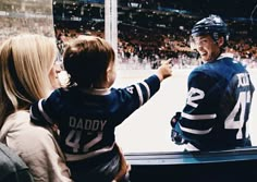 a young boy is being greeted by an ice hockey player and his mother at the rink