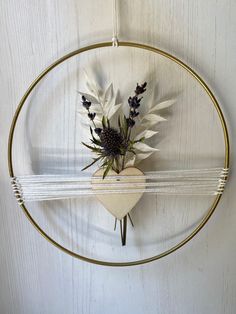 a metal circle hanging on the wall with flowers in it and some wire around it