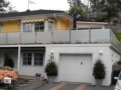 a yellow and white house with two cars parked in front of the garage door area