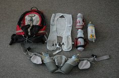 the contents of a backpack are laid out on the floor with water bottles and other items