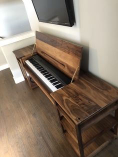 a wooden piano sitting on top of a hard wood floor next to a flat screen tv