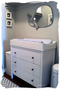 a baby's room with a dresser, mirror and changing table in the corner