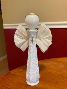 a white vase with a cross on it sitting on a table next to a red wall