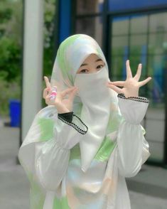 a woman in a hijab making the peace sign