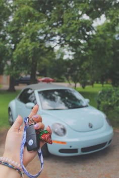 a person holding a car key in front of a blue car with a strawberry on it