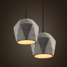 two concrete pendant lights hanging from a dark ceiling with light bulbs on each one side