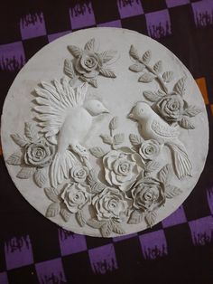 a white plate with flowers and birds on it sitting on a checkered tablecloth