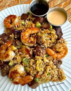 a white plate topped with rice and shrimp next to dipping sauce on top of it