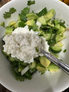 a white bowl filled with cucumbers and sour cream