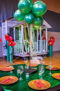 the table is set with green and yellow plates, orange napkins, and balloons