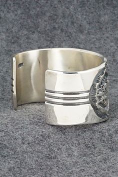 This stunning sterling silver bracelet was made by Navajo silversmith Jerrold Tahe. The inside is signed J. Tahe and stamped sterling.Size: 6" (will fit up to a 7 1/2" wrist)Gap: 1 1/2"Width: 1 1/2"Free shipping on all orders! We ship with USPS and always include tracking. All orders ship within a day of payment.Returns are accepted up to 30 days after you receive your order. Just send us a message. Our shop offers cash back or store credit. The item must be returned in new condition. Stamped Sterling Silver Wide Band Jewelry, Collectible Silver Bangle With Polished Finish, Collectible Wide Band Engraved Jewelry, Southwestern Silver Cuff Bracelet, Southwestern Hallmarked Silver Jewelry, Silver Artisan Bracelet, Collectible Engraved Wide Band Jewelry, Sterling Silver Southwestern Bracelet With Polished Finish, Silver Untreated Cuff Bracelet Gift