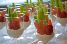 small glasses filled with dips and vegetables on a white tablecloth covered table cloth