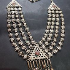 * This long, rusty silver necklace is embellished with fine floral elements, assembled in strings, making it one piece. The pendant is adorned with antique stone, dangling tassels, and floral motifs carved within the piece. This exclusive piece is an inspired style by Afghani kuchi ornaments, worn by the women of tribes as integral part of their cultural practices. You can pair this necklace with any traditional or trendy outfit, and it would get along any of the chosen fashion statements. Note: Boho Cuff Bracelet, Hand Cuff Bracelet, Kuchi Jewelry, Boho Cuff, Afghan Jewelry, Headpiece Jewelry, Antique Stone, Multi Layer Necklace, Layer Necklace