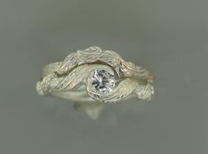 a close up of a ring with a diamond in the center and leaves on it